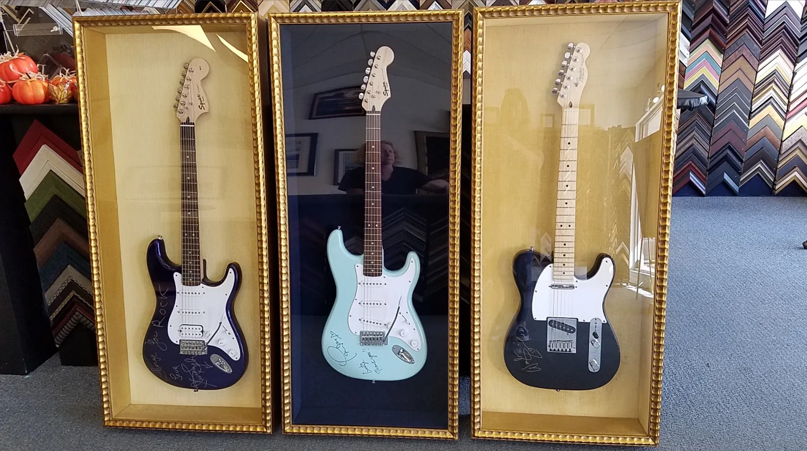 Three signed electric guitars mounted in gold beaded shadowbox frames, built at Luxe Frame Gallery