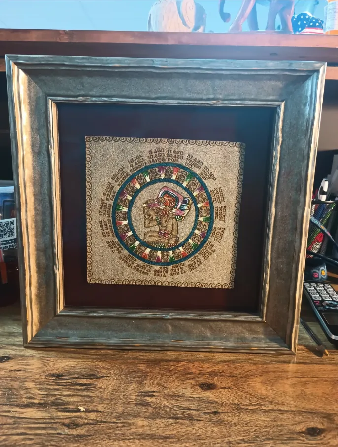 Framed Aztec-calendar textile with a deep mahogany mat in a distressed silver-and-black moulding